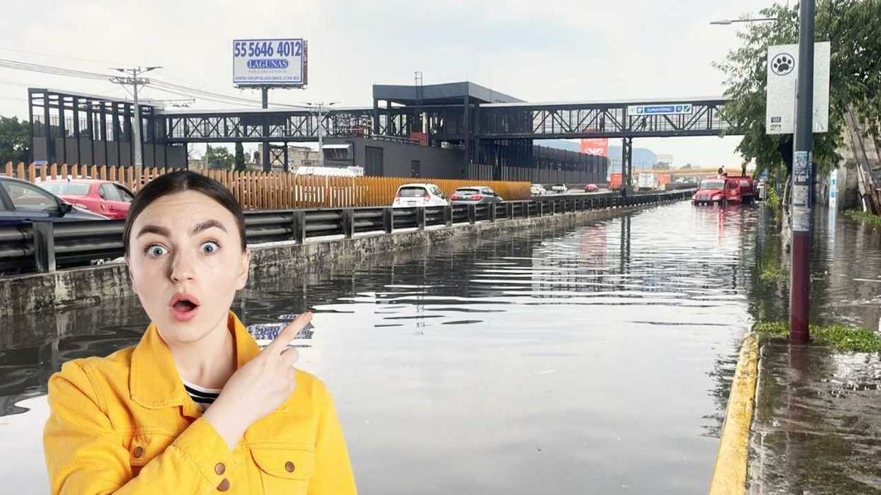 Person in yellow jacket points at a flooded street with cars partially submerged.
