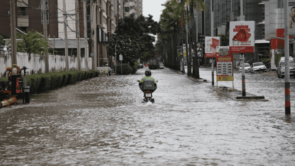 Person on motorcycle navigating flooded city street.