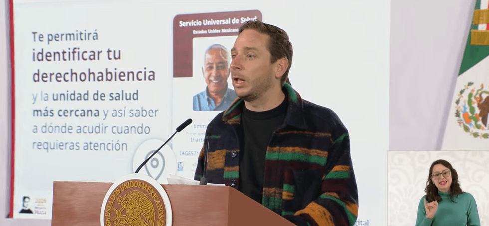 Person speaking at a podium about health services, with sign language interpreter visible.