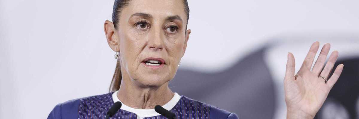 Person speaking at a podium, raising one hand.