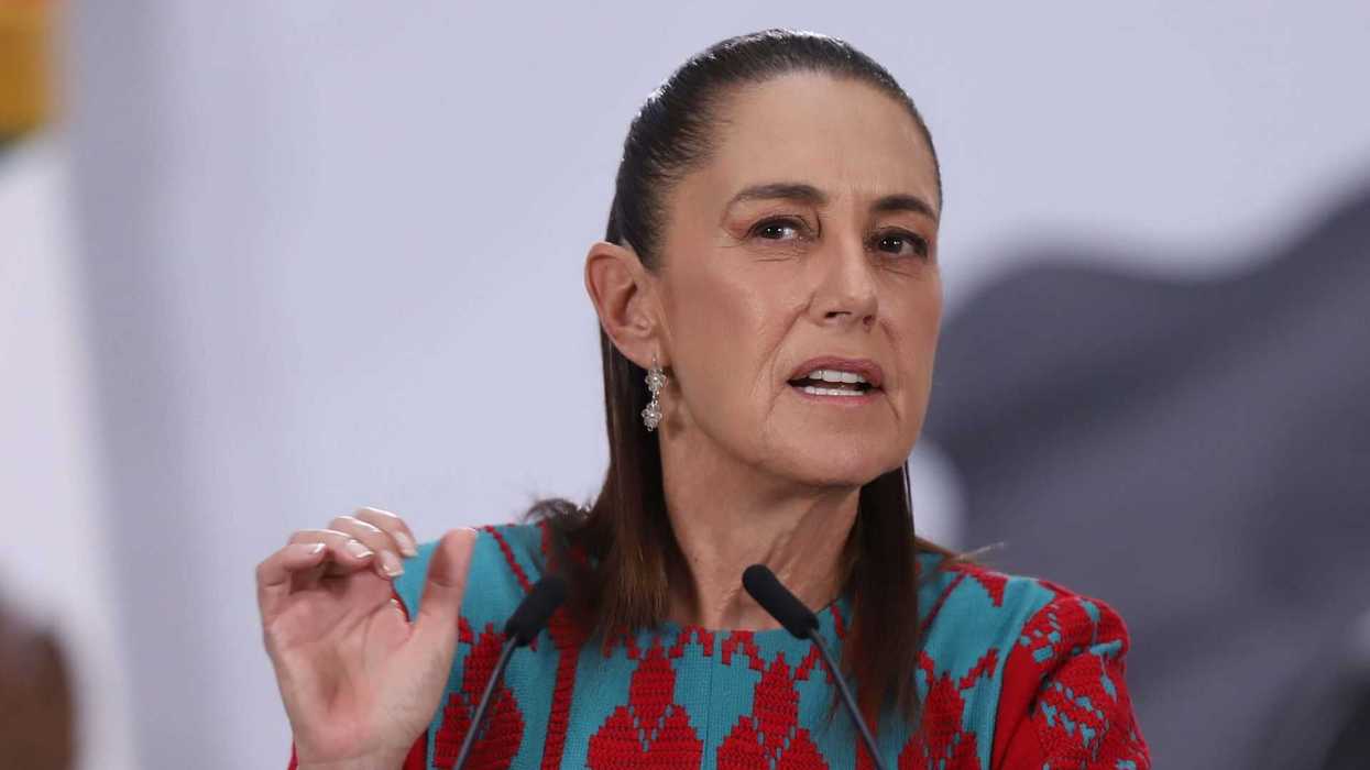 Person speaking at a podium, wearing a red and blue patterned outfit.