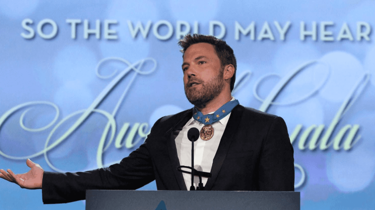 Person speaking at a podium with a medal, "So the World May Hear" in background.