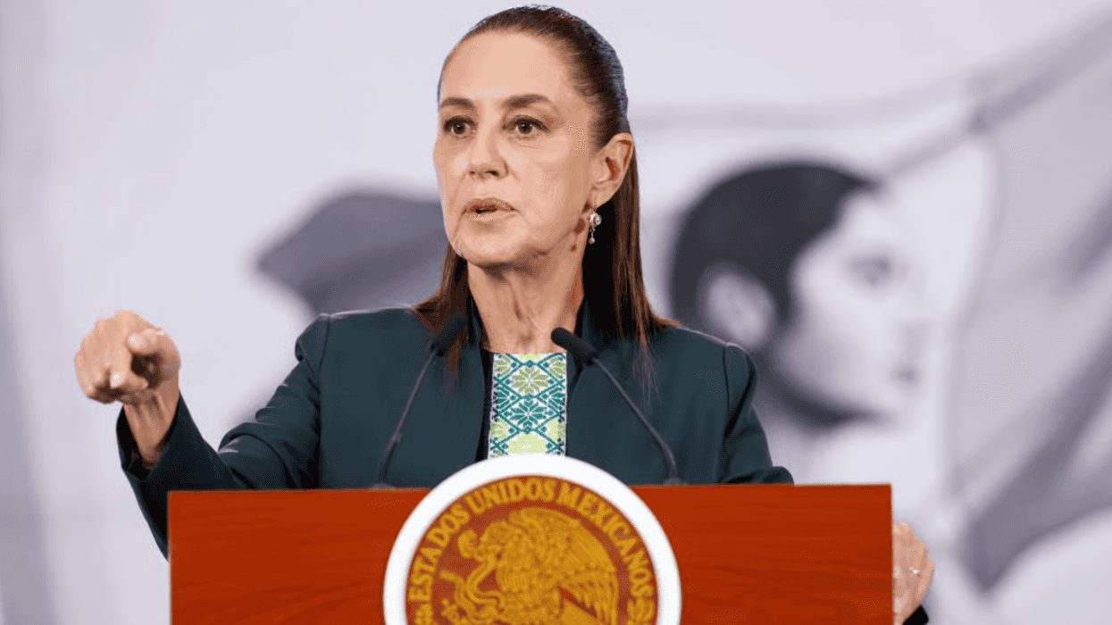 Person speaking at a podium with a seal, in front of a blurred background image.