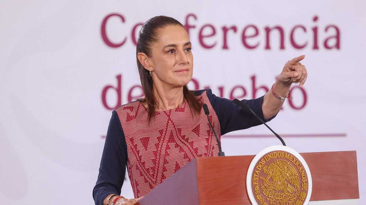 Person speaking at podium during a conference, pointing with one hand.