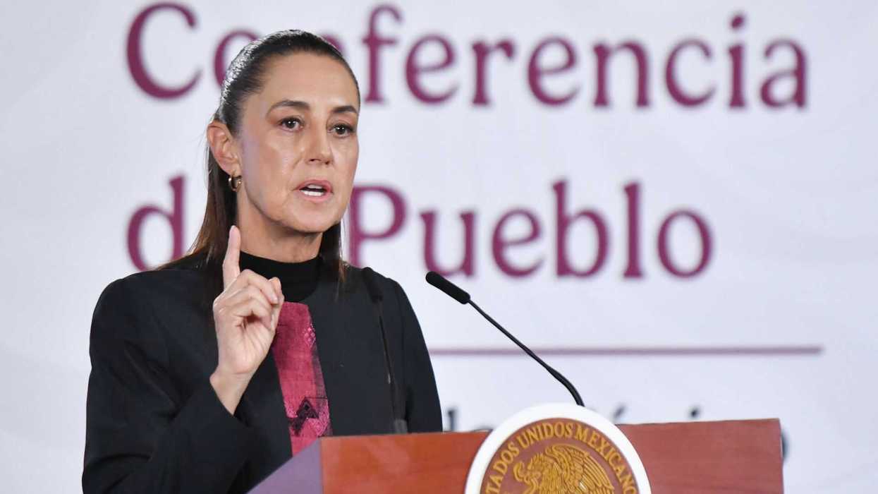Person speaking at podium during a press conference in front of a "Conferencia del Pueblo" sign.