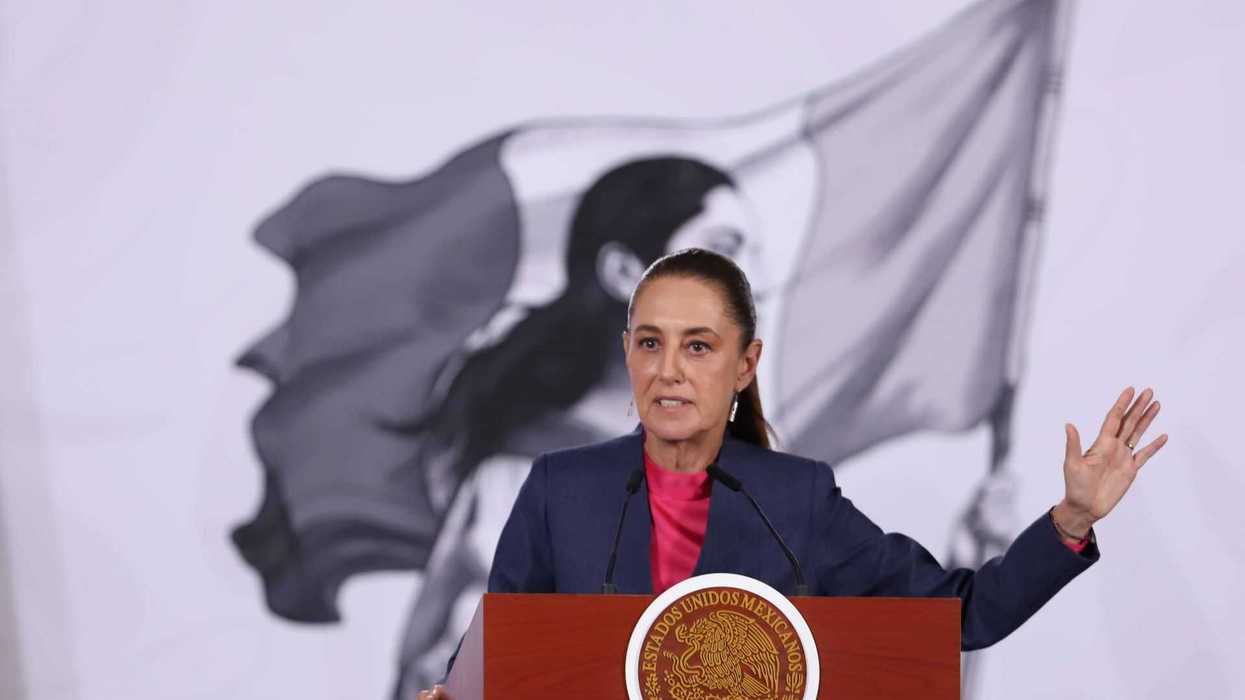 Person speaking at podium with Mexican emblem, flag in background.