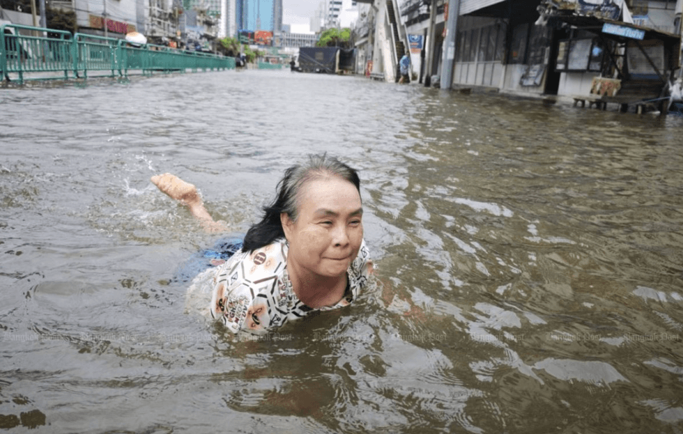 Person swimming through a flooded street in an urban area.