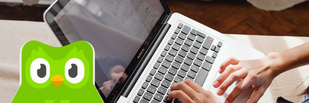 Person typing on a laptop with a Duolingo app logo overlay.