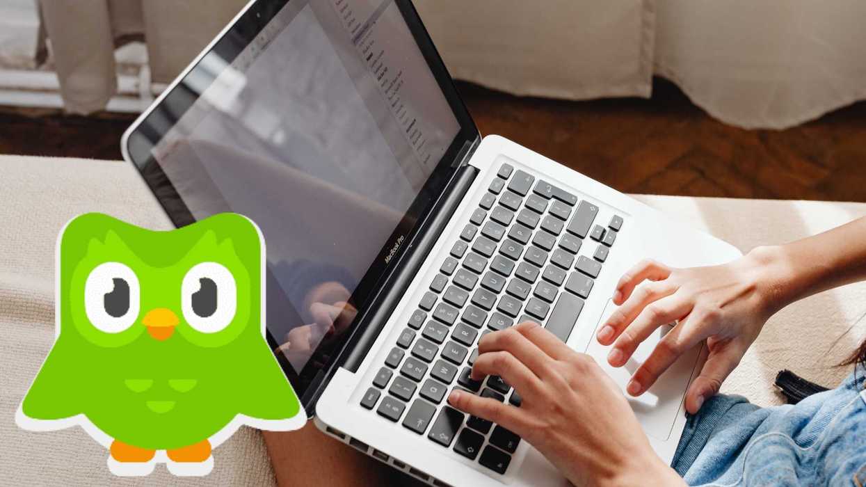 Person typing on a laptop with a Duolingo app logo overlay.
