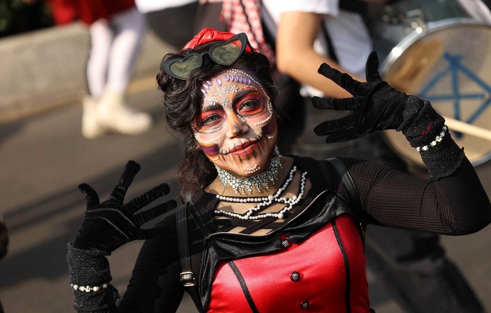 Person with face paint and costume poses with gloved hands in a festive event.
