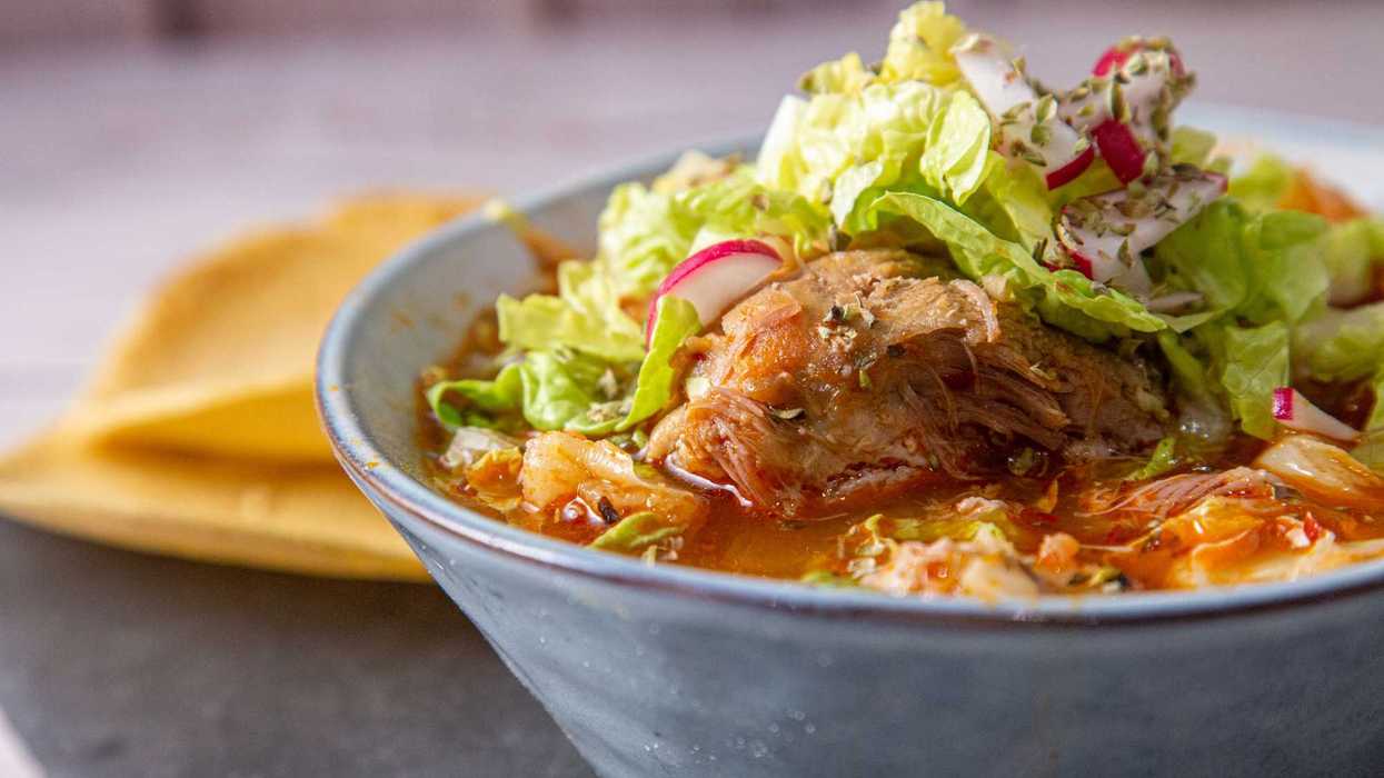 Plato de pozole mexicano con maíz cacahuazintle, carne de cerdo, lechuga, cebolla, rábanos y limón