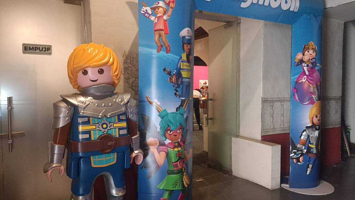 Playmobil knight figure beside a colorful, inflatable Playmobil-themed entrance arch.