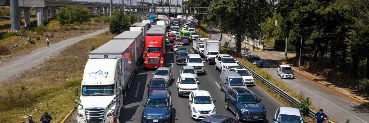 Protesters block a busy highway, holding banners, causing a traffic jam.