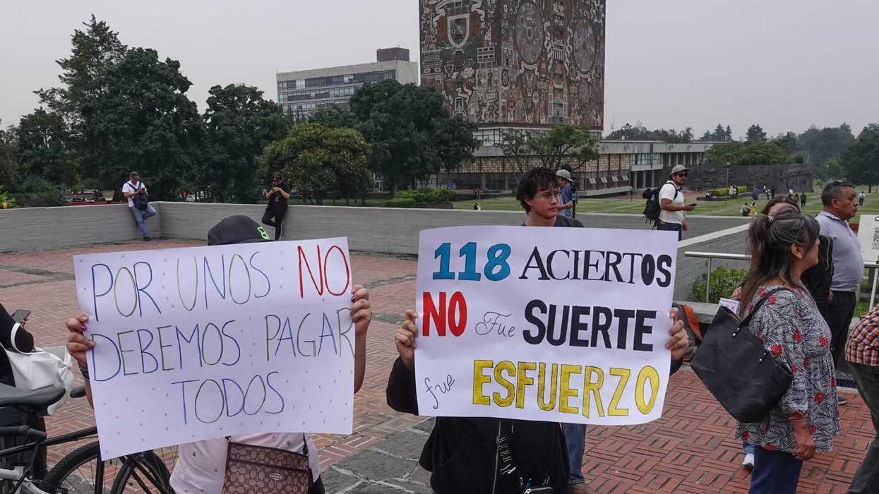 Protesters holding signs in front of a mural-covered library building.