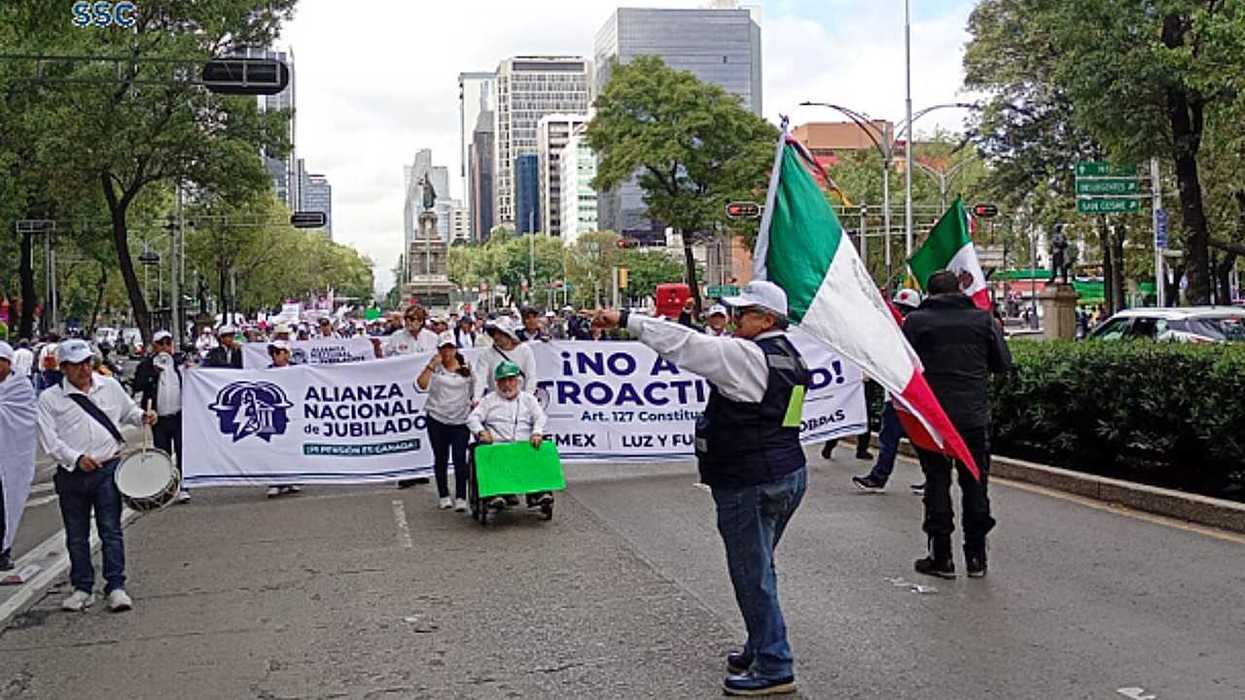 Protesters march with banners and flags on a city street.