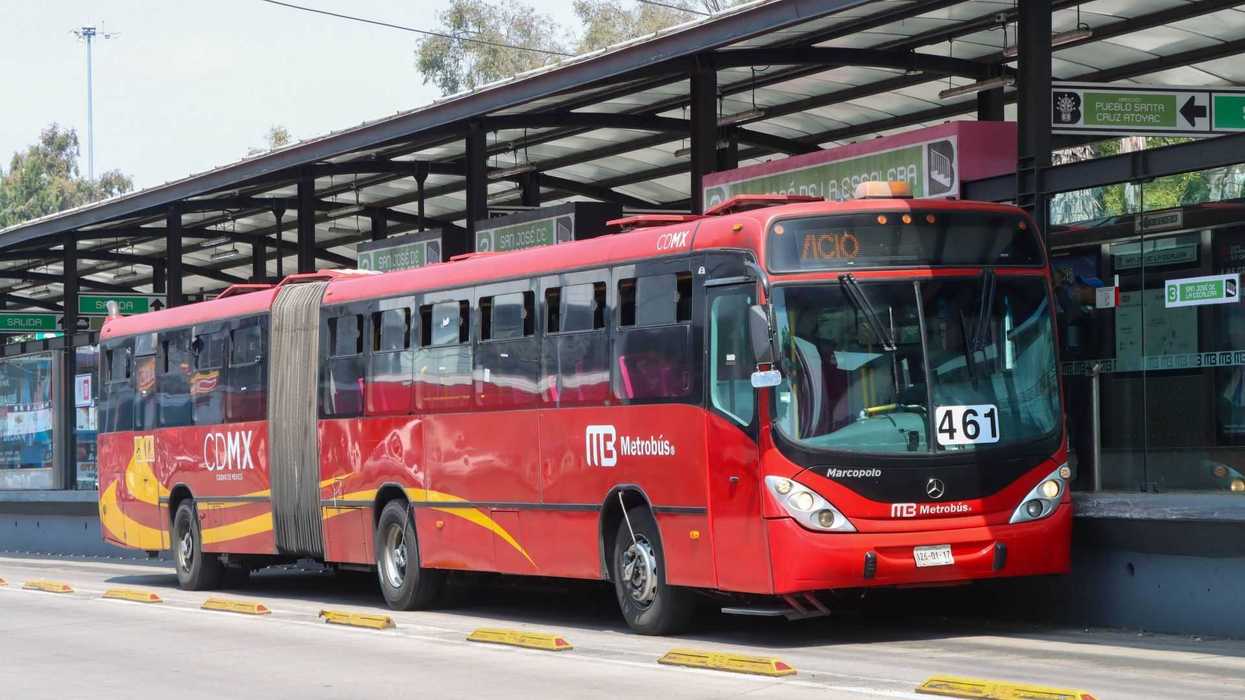 Red articulated Metrobus at a station platform in Mexico City.