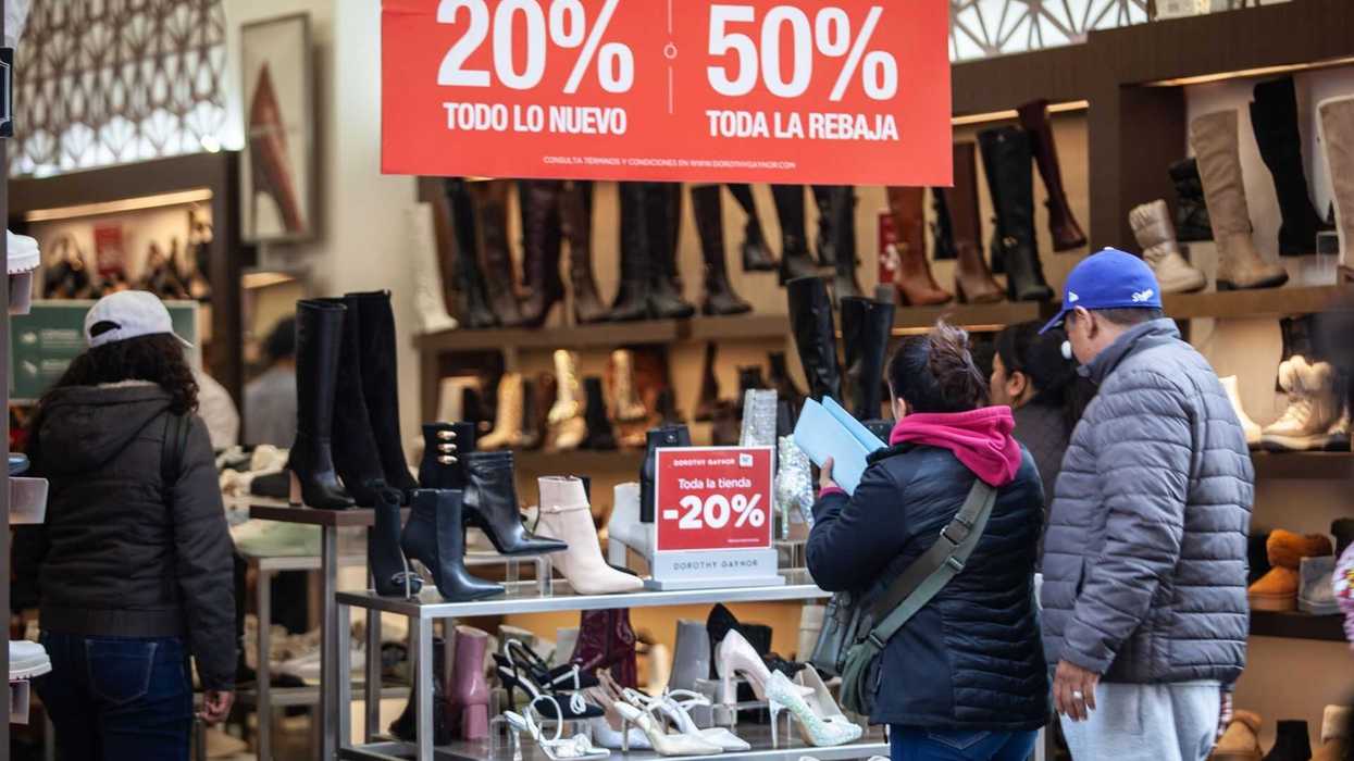Shoppers browse boots at store with 20%-50% sale sign overhead.