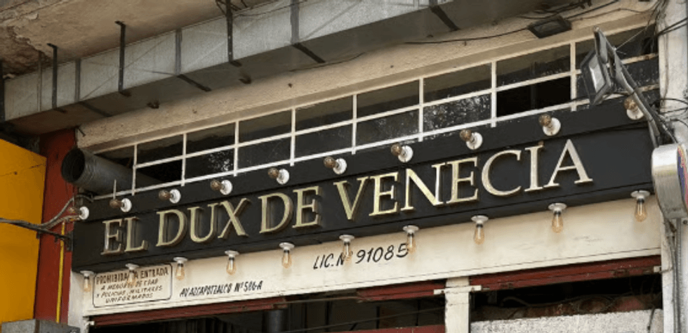 Sign reading "El Dux de Venecia" with lights and a small information board below.
