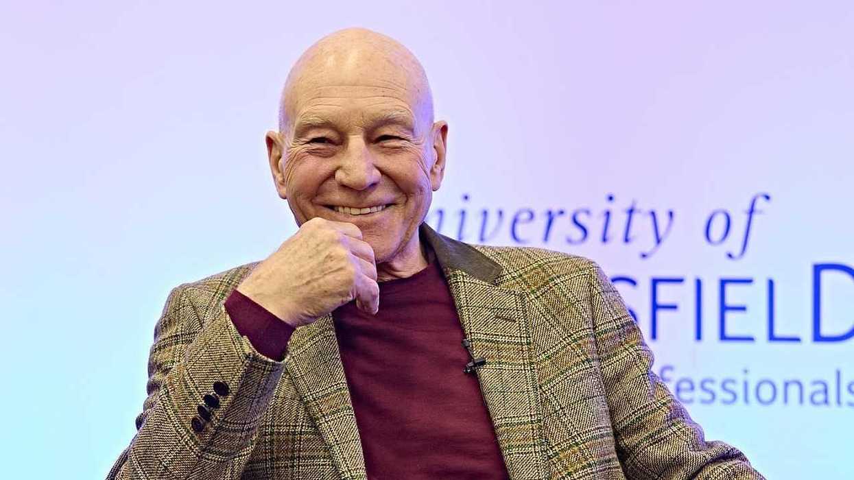 Smiling bald man in a plaid blazer poses before a University of Sheffield backdrop.