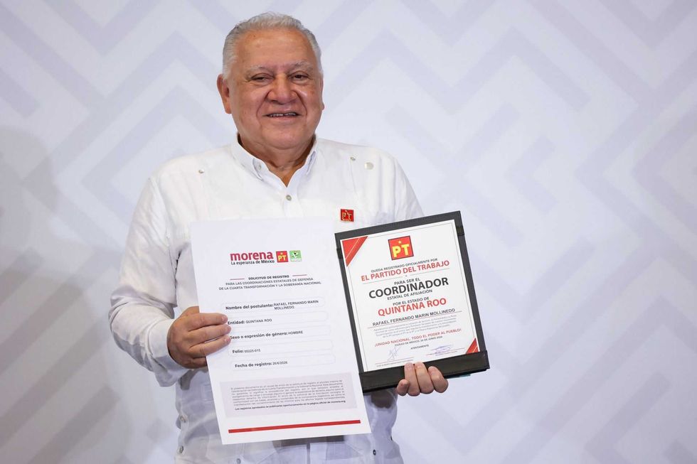 Smiling man holding certificates against a geometric patterned background.