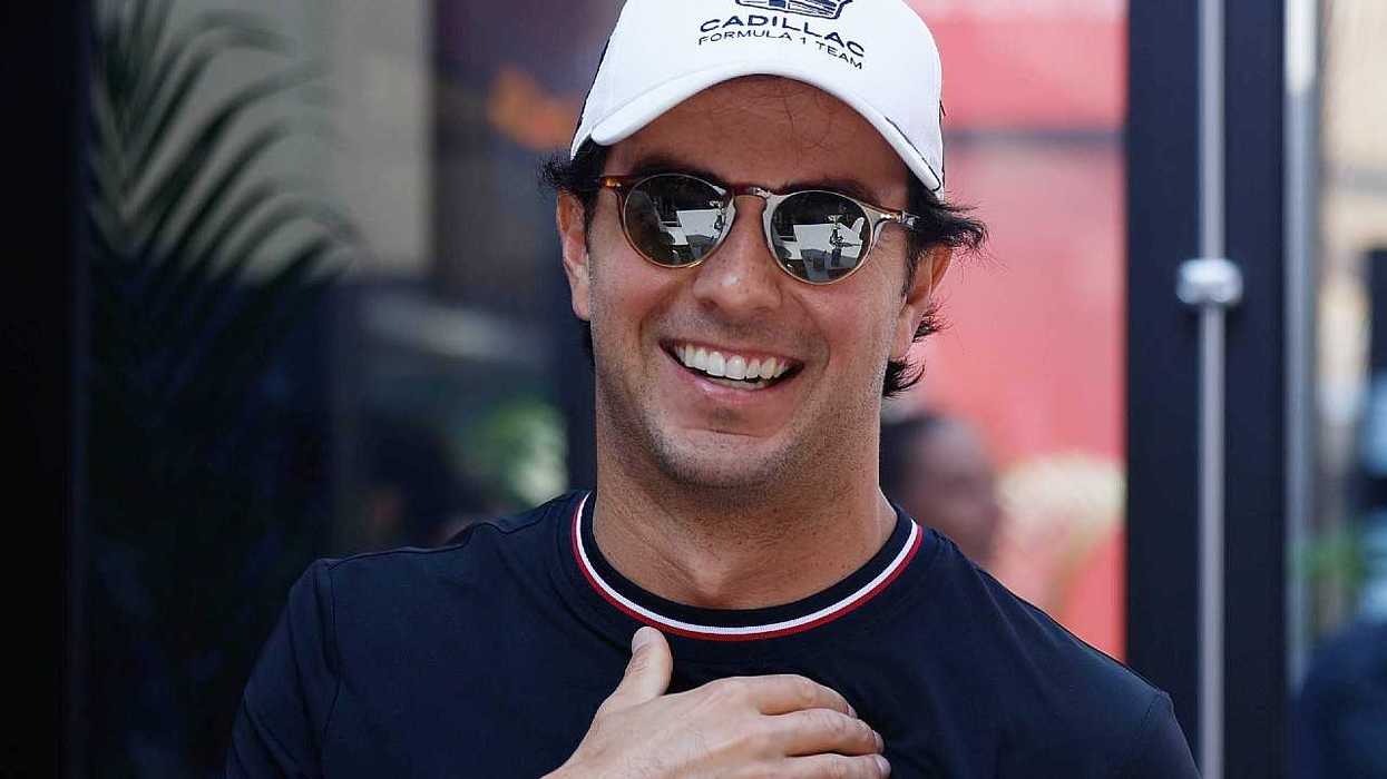 Smiling man in sunglasses and a white Cadillac Formula 1 team cap.