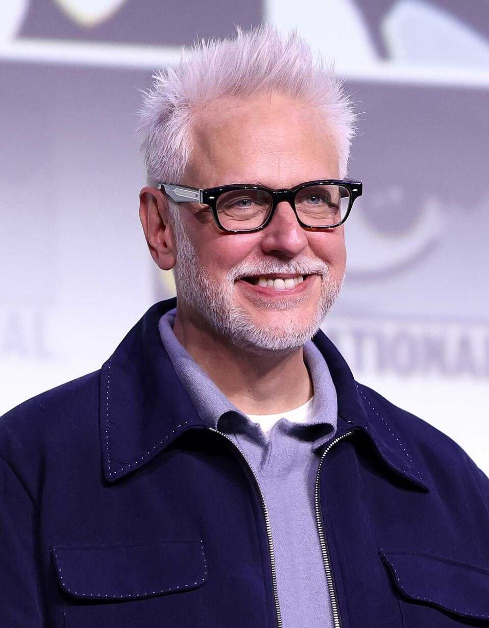 Smiling man with white hair, glasses, and a beard wearing a dark jacket on stage.