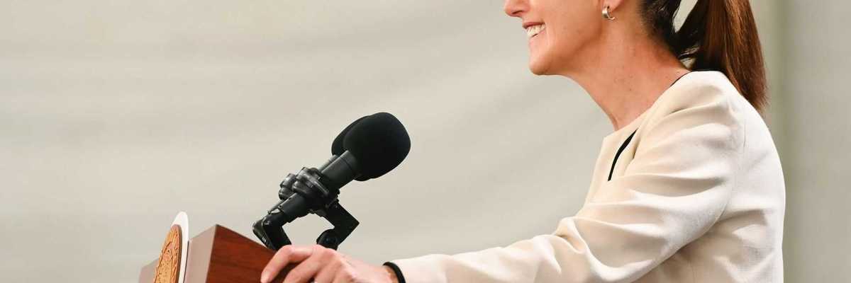Smiling woman speaking at a podium with a microphone.