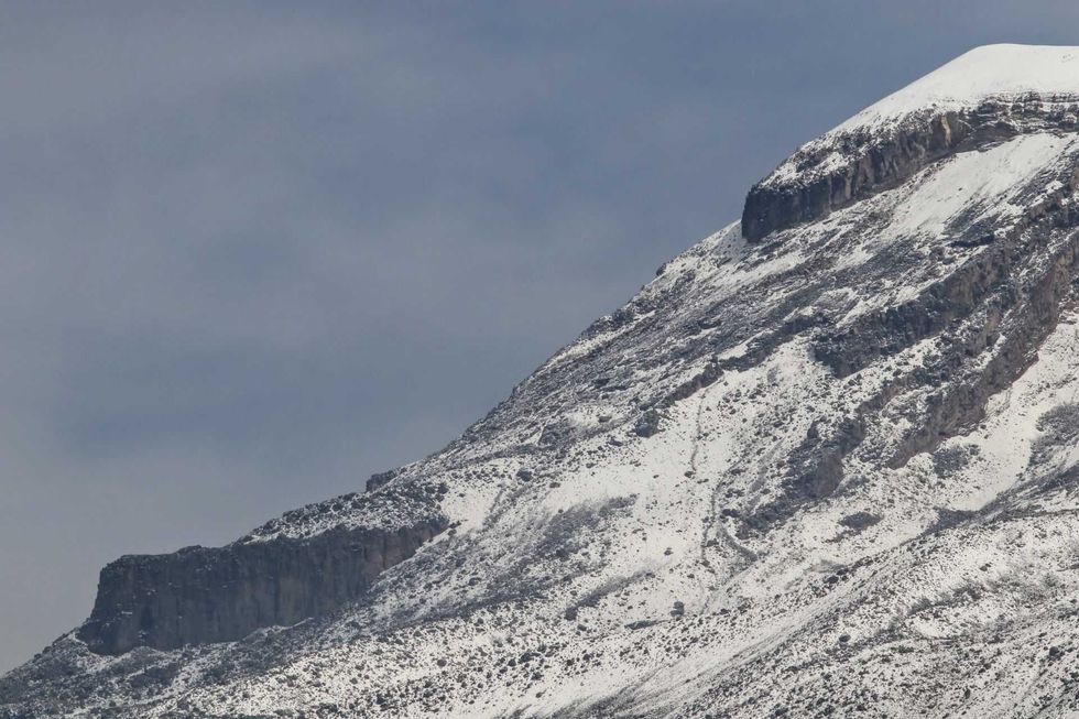 Snow-covered mountain peak under a cloudy sky.