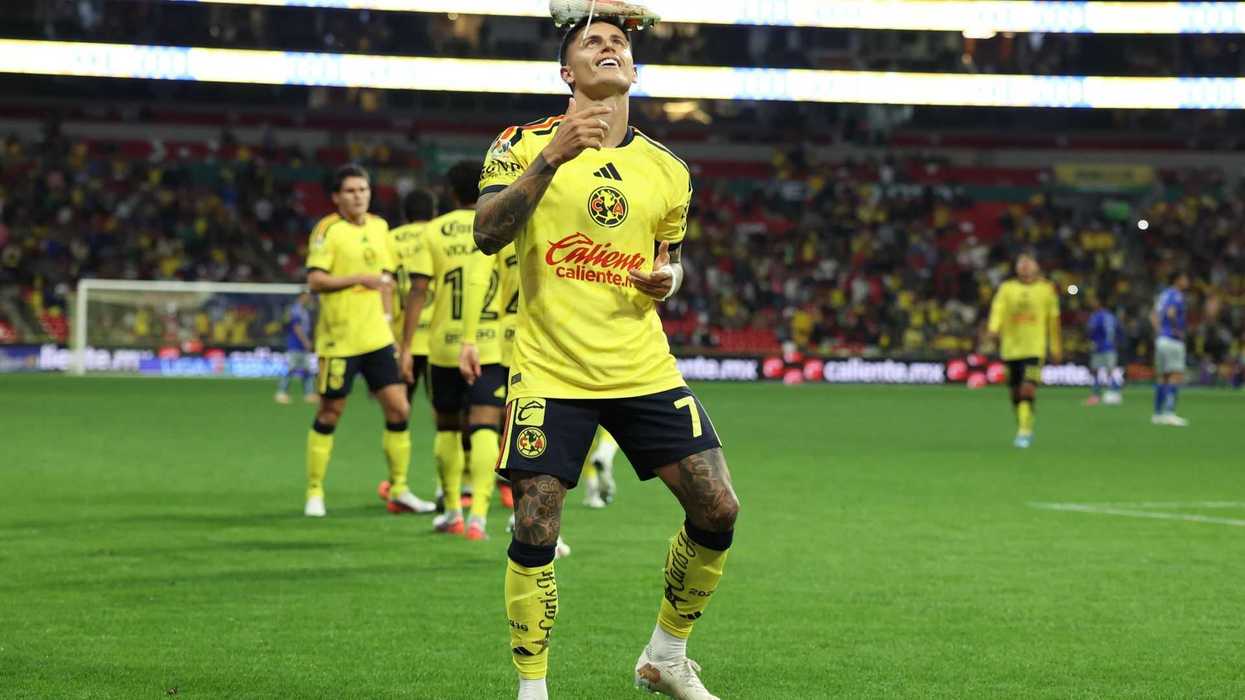Soccer player balancing a shoe on his head during a match, wearing a yellow jersey.