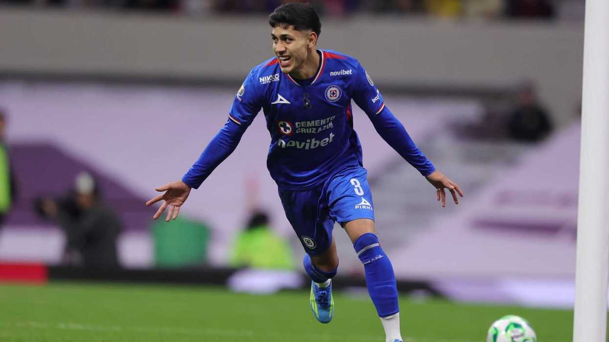 Soccer player in blue jersey celebrating a goal on the field.