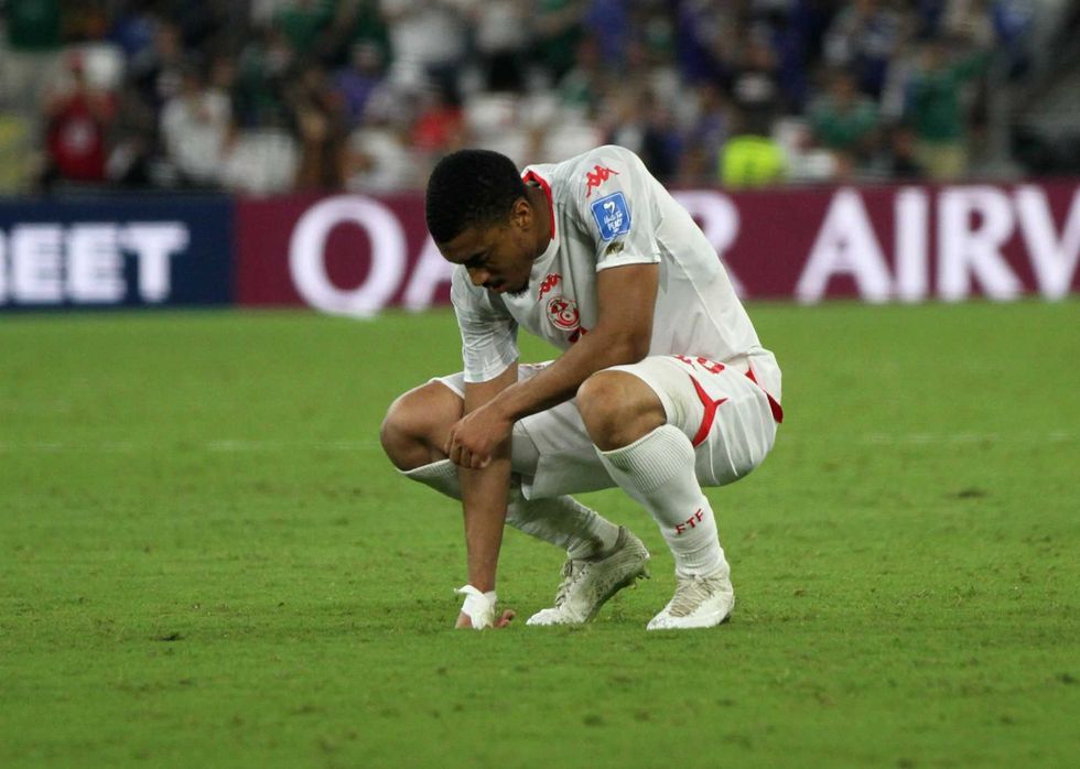 Soccer player kneeling on the field in contemplation during a match.