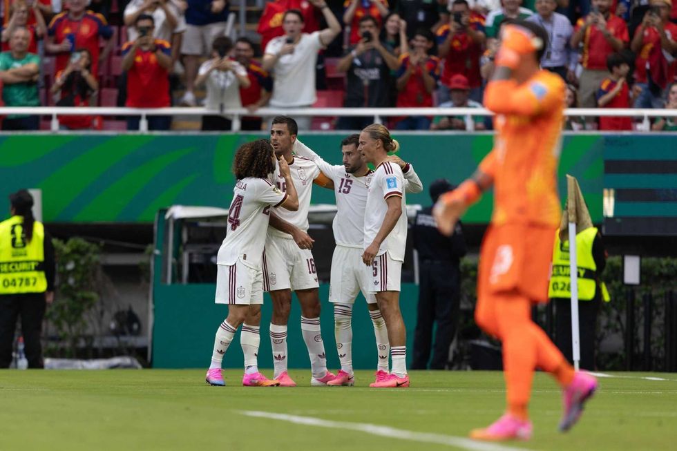 Soccer players celebrate a goal as the crowd cheers in a vibrant stadium.
