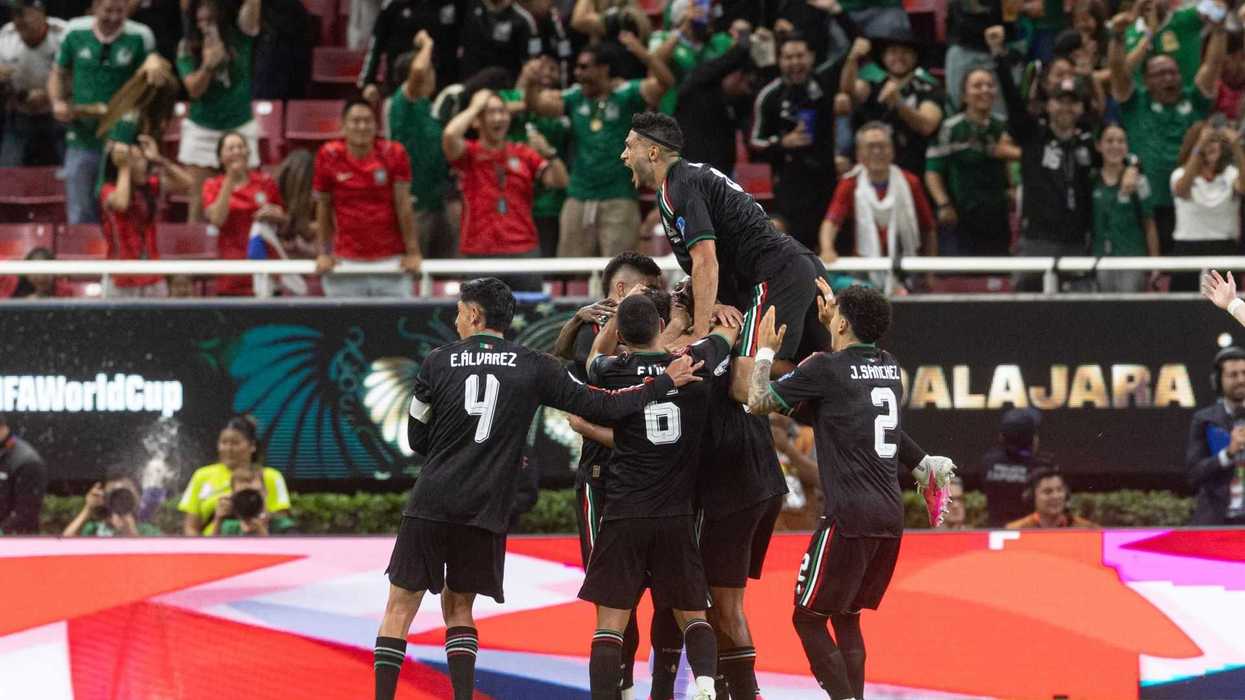 Soccer players celebrating a goal with cheering fans in a packed stadium.
