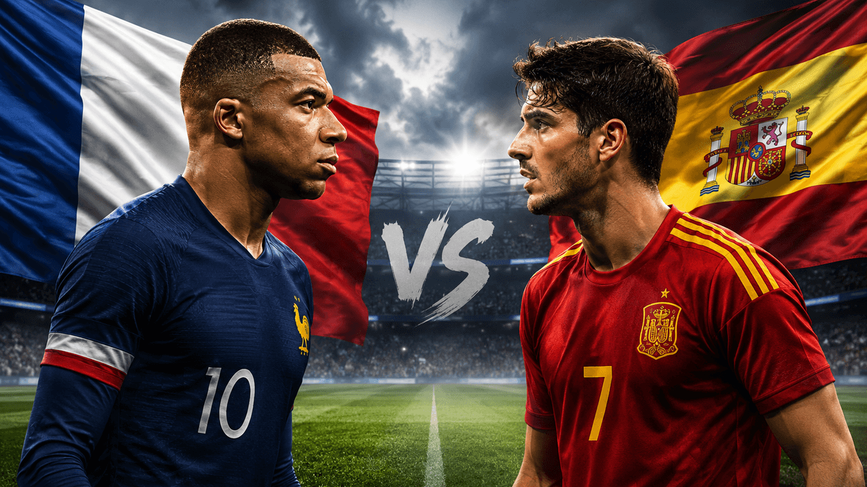 Soccer players facing off with France and Spain flags in background.