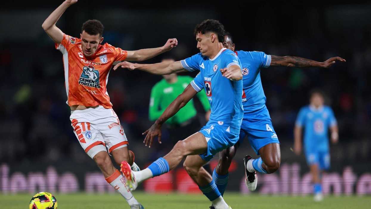 Soccer players from rival teams vie for ball possession on the field.