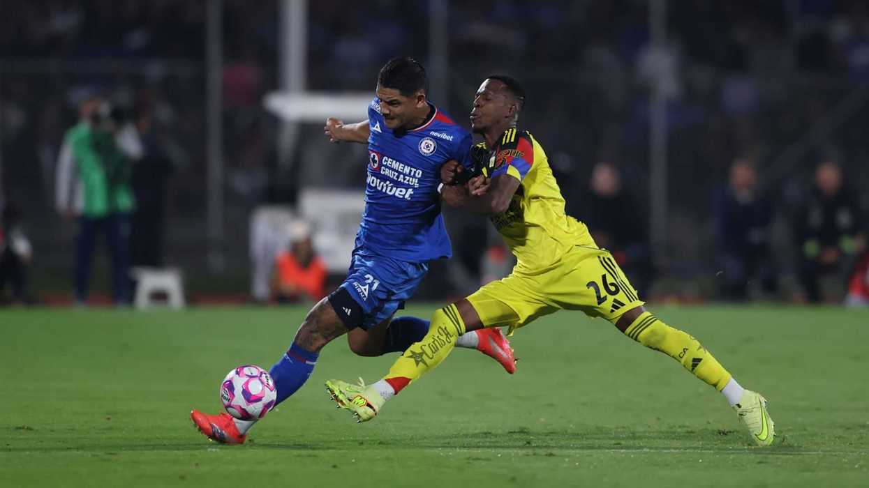 Soccer players in blue and yellow jerseys compete for ball possession on the field.