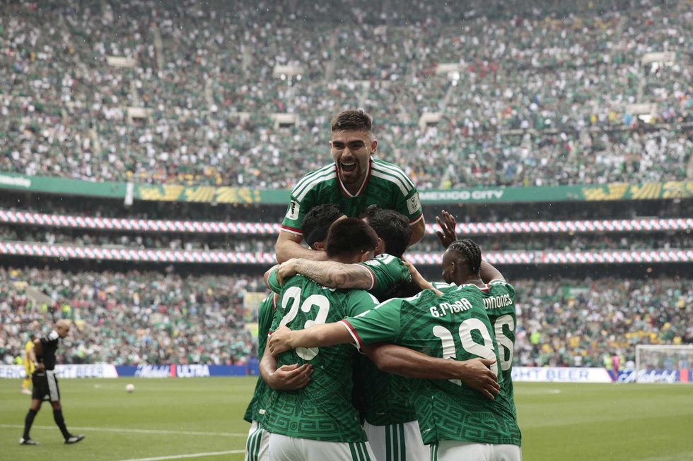 Soccer players in green jerseys celebrate a goal in a filled stadium.
