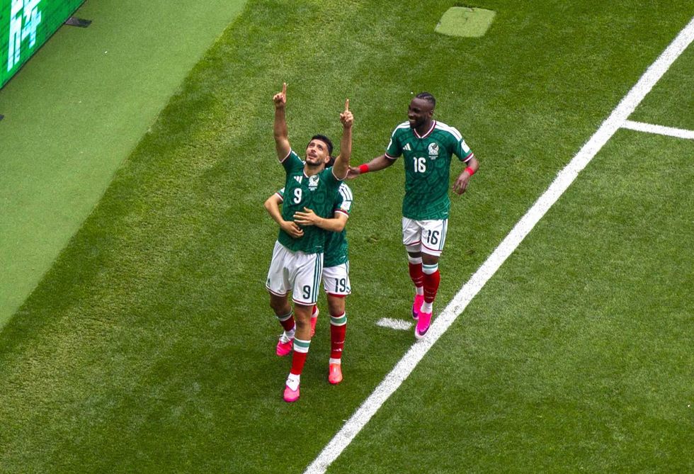 Soccer players in green uniforms celebrating a goal on the field.