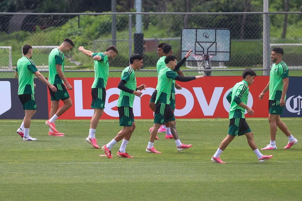 Soccer players in green uniforms training on a field, with advertising boards in the background.