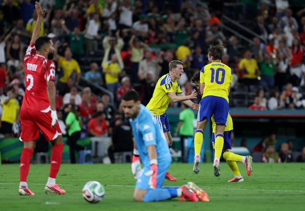 Soccer players in yellow jerseys celebrate, opposing team in red reacts, crowd in background.