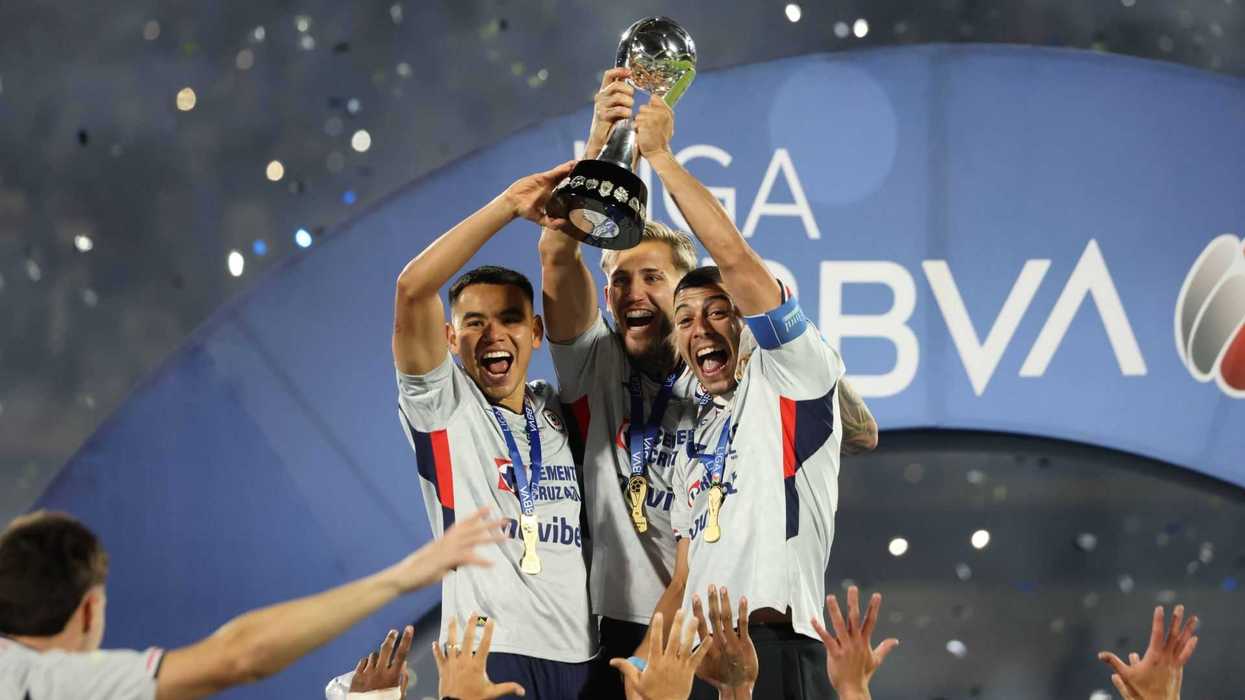 Soccer players jubilantly lift the Liga BBVA trophy, celebrating their victory.