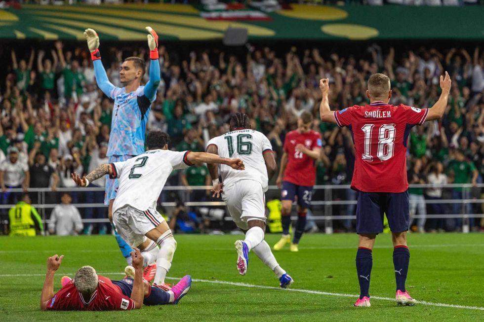 Soccer players react during a match; one player on the ground, others gesturing.