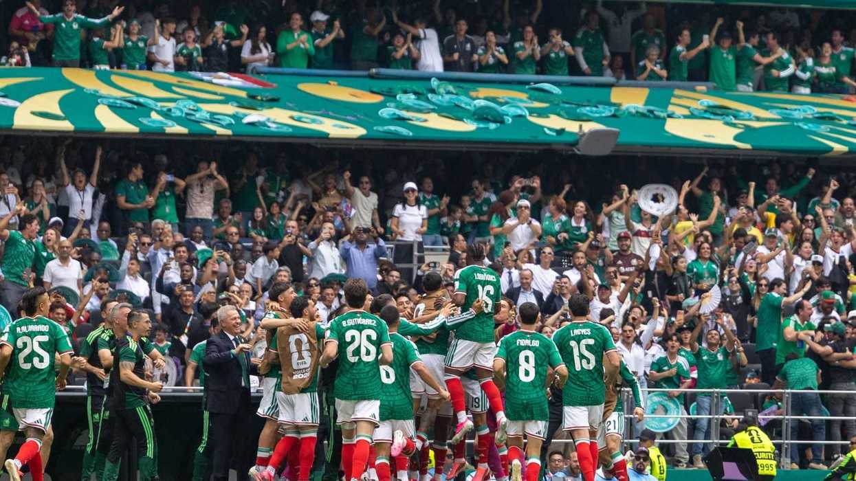 Soccer team celebrating a goal with cheering fans in a stadium.