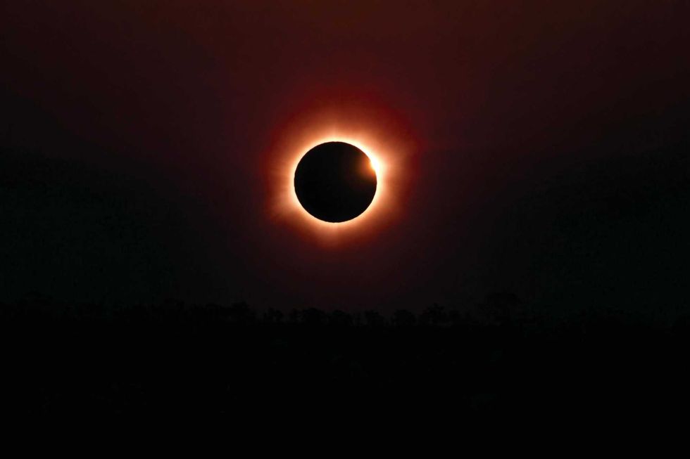 Solar eclipse with a glowing corona against a dark sky.