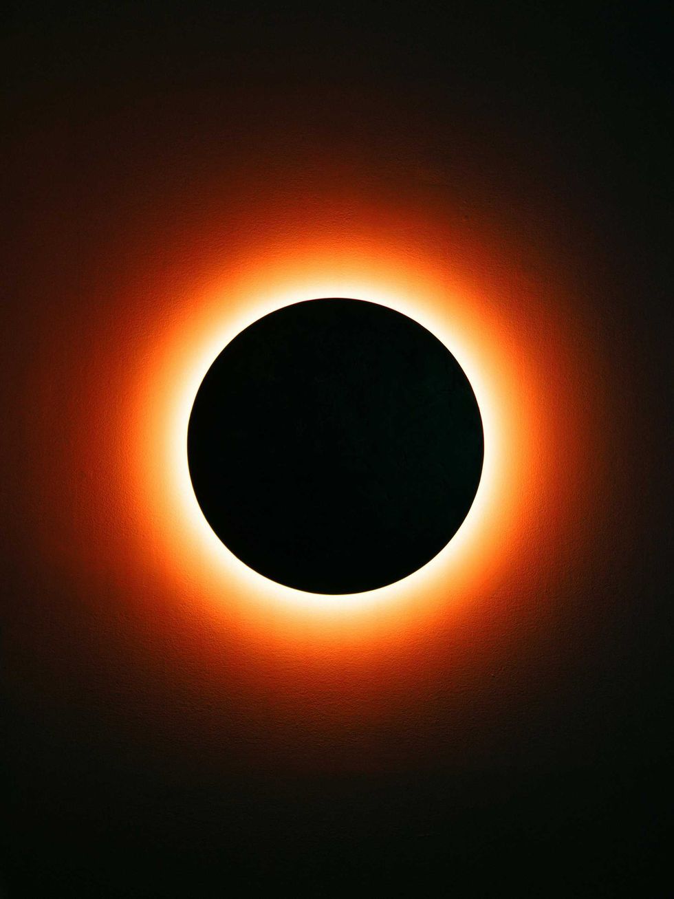 Solar eclipse with glowing orange ring against a black circle.