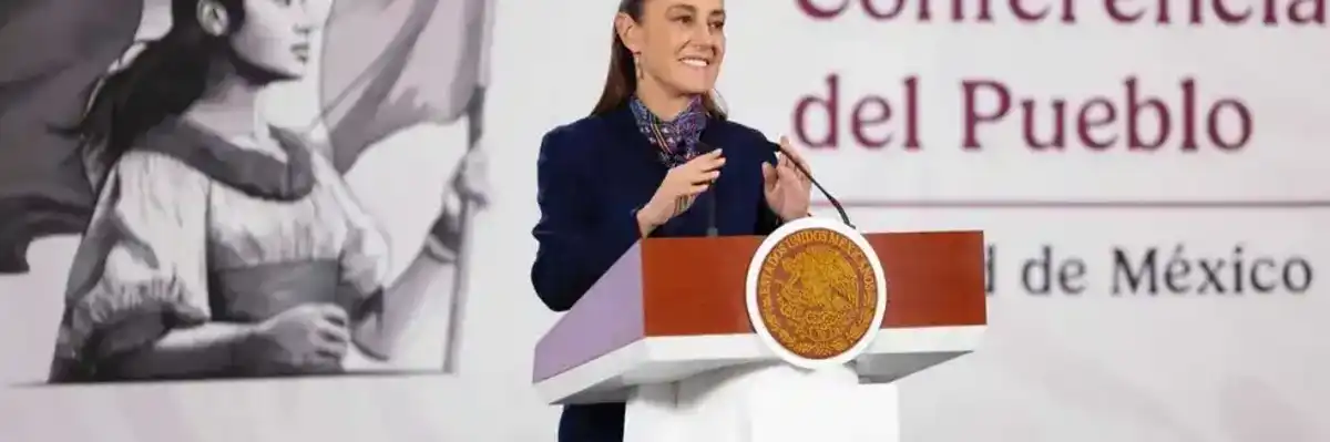 Speaker at a podium during "Conferencia del Pueblo," with large mural in the background.