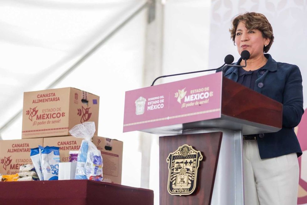 Speaker at podium with food boxes labeled "Estado de M\u00e9xico."