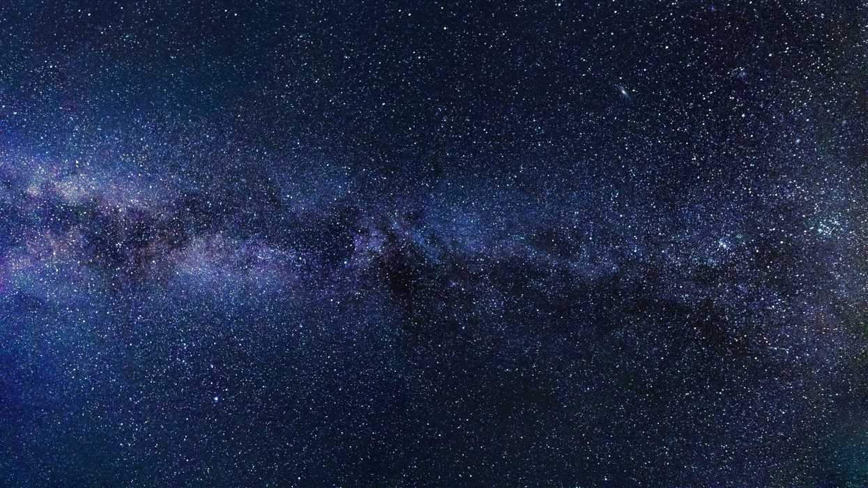 Starry night sky with dense cluster of stars and faint Milky Way galaxy band.