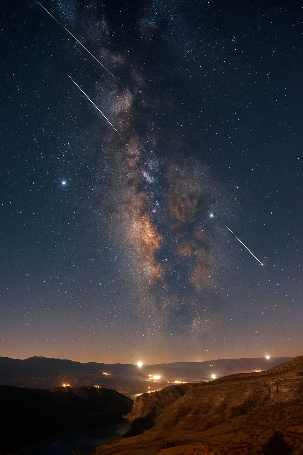 Starry night sky with Milky Way and distant mountains.