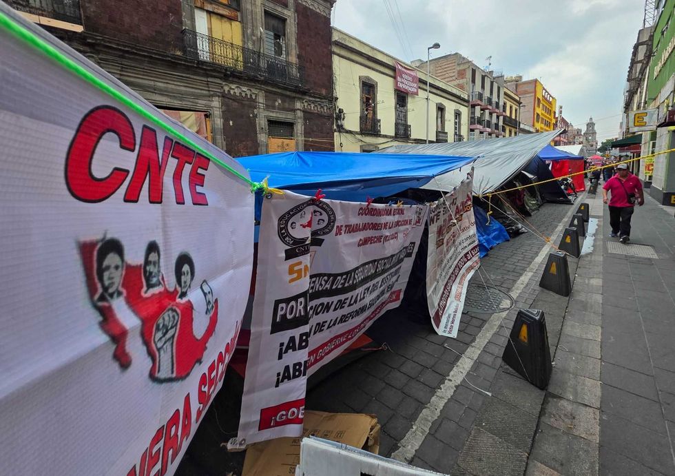 Street protest with banners and tents set up along a city road.